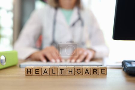 Photo for Close-up of healthcare word collected with wooden cubes in row. Woman doctor in medical gown on background. Medicine, treatment and wellbeing concept - Royalty Free Image