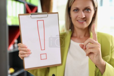 Photo for Portrait of smiling woman holding clipboard with red exclamation point. Interjection and exclamatory concept - Royalty Free Image