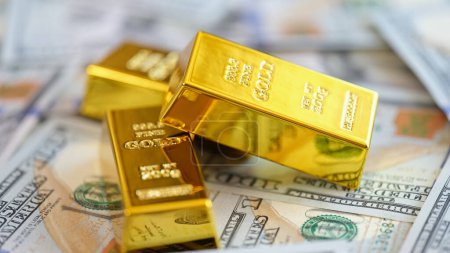 Goldbarren auf US-Dollar-Banknoten im Hintergrund. Goldpreis, Wechselkurse und Anlagekonzept.
