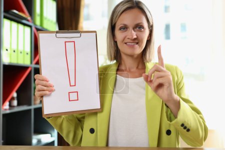Photo for Business woman holding clipboard with exclamation mark in her hand in office. Concept of attention and important information. - Royalty Free Image