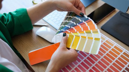 Téléchargez les photos : Designer choosing colors for his future project in art studio. Close up of manager and many color samples on office table. - en image libre de droit