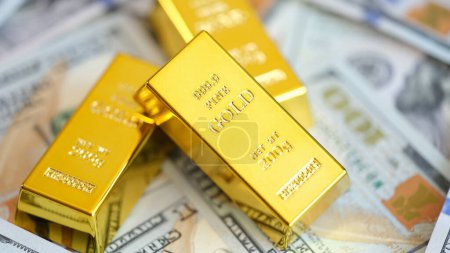 Foto de Close up of gold bars on many US dollar bills. Gold trading, exchange rates and saving money concept. - Imagen libre de derechos