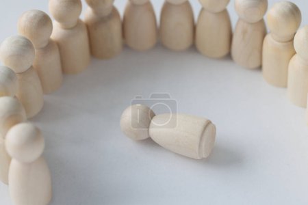Photo for One wooden figure laying in circle of many people figures. Discrimination, crimes and violence concept. - Royalty Free Image