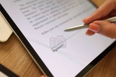 Foto de Close-up of female hand signing e-document with stylus on tablet. Electronic signature and modern technologies concept - Imagen libre de derechos