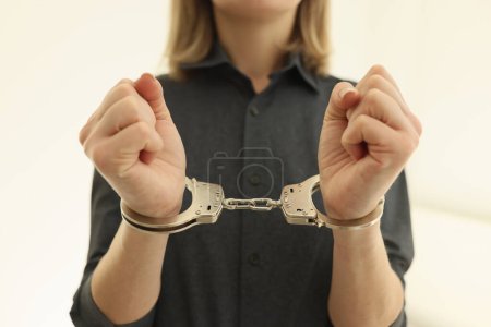 Photo for Woman with metal handcuffs in prison cell closeup. Arrest of criminal for judgement in state court. Inevitability of punishment for illegal actions - Royalty Free Image