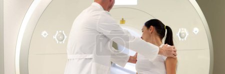 Photo for Portrait of doctor helping patient lie down for mri procedure. Patient at medical consultation. Magnetic resonance imaging and healthcare concept - Royalty Free Image