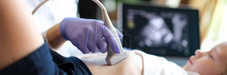 Foto de Close-up of doctor examining with ultrasound of internal organs of child in clinic. Ultrasound of abdominal cavity procedure concept - Imagen libre de derechos