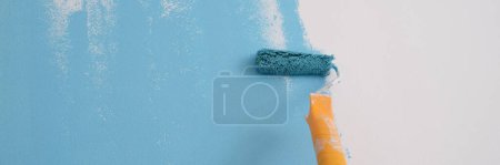 Téléchargez les photos : Gros plan du mur de peinture décorateur professionnel en couleur bleue. Peinture de murs avec rouleau. Concept de réparation et rénovation - en image libre de droit
