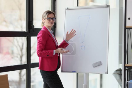 Portrait of smiling woman near presentation board showing exclamation point. Interjection and exclamatory concept