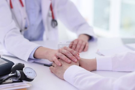 Photo for Doctor holds male client hands during consultation sitting at light table in clinic office. Specialist supports patient with complicated disease - Royalty Free Image
