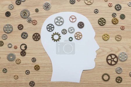 Image de tête humaine en papier avec de petites roues dentées sur une surface en bois. Amélioration de l'état d'esprit et concept de santé mentale. Stratégie de maintenance du cerveau
