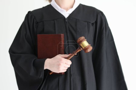 Photo for Woman judge in classic gown holds corpus juris book and wooden mallet in studio. Public official listens cases in law court. Juridical decision maker in law - Royalty Free Image