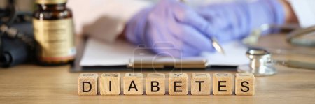Photo for Close-up of diabetes word collected with wooden blocks in row. Female endocrinologist writing prescription. Diagnosis and treatment of diabetes mellitus - Royalty Free Image