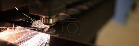 Close-up of metal cutting process and fire sparks flying out. Laser cutting machine, metal sheet and fiery particles. Manufacturing and production concept