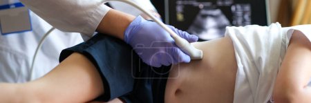 Téléchargez les photos : Close-up of doctor making examining with ultrasound of internal organs of child in clinic office. Ultrasound of abdominal cavity procedure concept - en image libre de droit