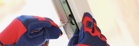 Hands of master with screwdriver repairing adjustment or installation of metal-plastic windows in apartment. Glazing of balconies loggias and verandas in house