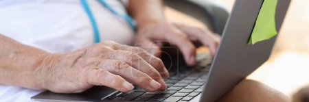 Photo for Hands of elderly woman typing on laptop keyboard closeup. Searching for information on Internet for pensioners - Royalty Free Image