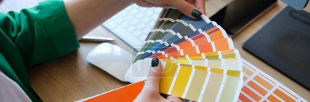 Téléchargez les photos : Designer choosing colors for his future project in art studio. Close up of manager and many color samples on office table. - en image libre de droit