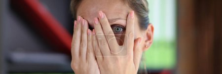 Téléchargez les photos : Frightened woman covers her face with her hands and looks through her fingers at camera close-up. Concept of mistake, fear and stress. - en image libre de droit