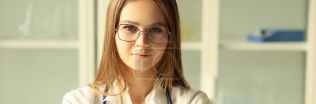 Téléchargez les photos : Young pretty female doctor in glasses with stethoscope looking at camera. Female intern working in medical clinic, medical education concept. - en image libre de droit