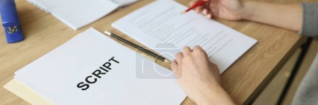 Photo for Actress checks script papers for filming movie making notes with pencil. Woman edits text at wooden table in office and prepares for playing role - Royalty Free Image