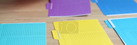 Photo for Secretary itemizes multi-colored folders with accounting documents on wooden table. Woman sorts out materials with data at workplace in office - Royalty Free Image