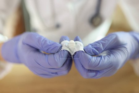 Nahaufnahme von Ärzten Hände in Handschuhen öffnen Zäpfchen für analen oder vaginalen Gebrauch. Unverpackte medizinische Kerze zur Behandlung von Hämorrhoiden, Entzündungen.