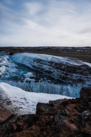 paisaje de una enorme cascada nevada y helada con cielo azul y paisajes otoñales