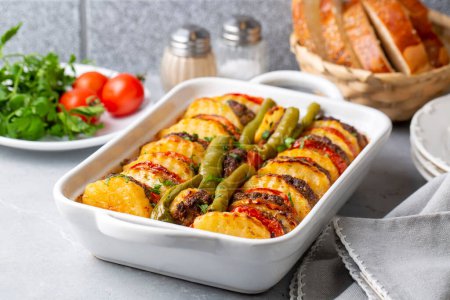 Photo for Traditional Turkish food; baked potatoes and meatballs. Turkish name; kofteli patates dizmesi, patates dizme - Royalty Free Image