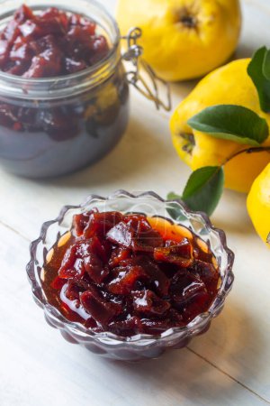 Foto de Homemade quince jam in a glass jar on an old wooden background. Fresh quince fruits and leaves and quince jam. (Turkish name; ayva receli) - Imagen libre de derechos