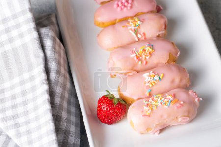 Téléchargez les photos : Délicieux dessert français éclair à la crème vanille et sauce fraise sur assiette blanche. - en image libre de droit