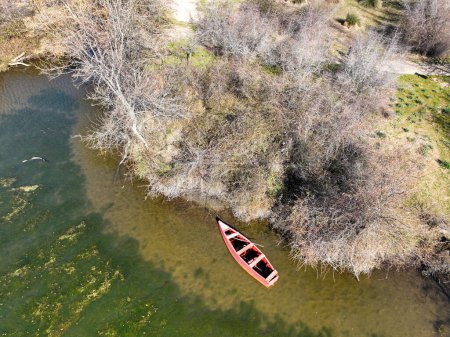 Foto de Aerial drone view of red small boat on Longoz forest lake in winter season. Karacabey Longoz Forests. Karacabey, Bursa,Turkey - Imagen libre de derechos
