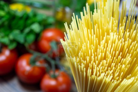 Foto de Pasta cruda de espagueti sin cocer con verduras en el fondo - Imagen libre de derechos