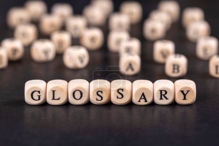 Glosario - palabra de bloques de madera con letras, lista alfabética con significado de palabras concepto de glosario, letras aleatorias alrededor, vista superior sobre fondo gris