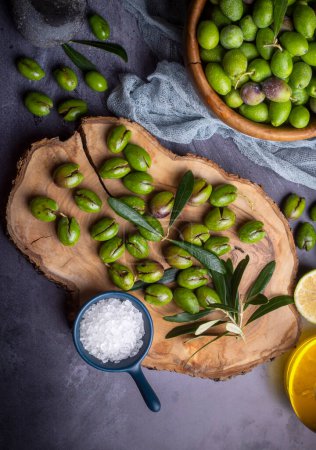 Téléchargez les photos : Fabriqué maison concassant olive. Les olives vertes fraîches cassent une par une. Broyer les olives avec de la pierre. Préparation d'olives marinées à la turque. (nom turc ; kirma zeytin) - en image libre de droit