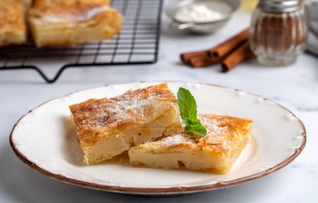 Photo for Greek pie called Bougatsa with cheese slightly blurred cross section and selective focus on powdered sugar and cinnamon - Royalty Free Image