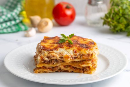 Photo for Portion of ground beef lasagna topped with melted cheese and garnished with fresh parsley served on a plate in close view for a menu - Royalty Free Image
