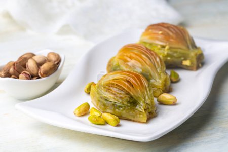 Téléchargez les photos : Midye Baklava turc (forme de moule Baklava) avec de la poudre de pistache verte et crème au beurre. Conceptuel des fêtes islamiques. - en image libre de droit