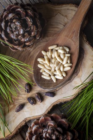 Téléchargez les photos : Noix de pin dans la cuillère et cône de noix de pin sur la table en bois. Aliments biologiques
. - en image libre de droit