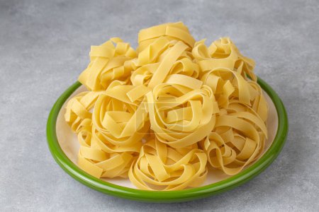 Photo for Homemade egg pasta tagliatelle. Raw nest noodles, uncooked ribbon fettuccine, dry long rolled macaroni - Royalty Free Image
