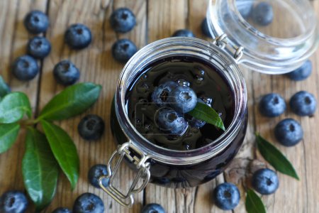Blueberry jam in jar with berries and leaves