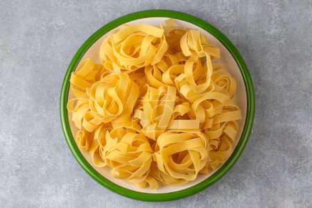 Photo for Homemade egg pasta tagliatelle. Raw nest noodles, uncooked ribbon fettuccine, dry long rolled macaroni - Royalty Free Image