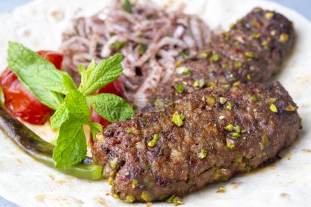 Photo for Traditional delicious Turkish cuisine, kebab type belonging to Adana and Antep regions, grilled pistachio kebab. Turkish name; fistikli kebab - Royalty Free Image