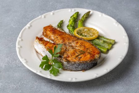 Photo for Grilled, baked salmon served on a plate with asparagus and potatoes. - Royalty Free Image