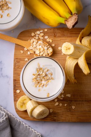 Photo for Vegan banana and oatmeal smoothie in glass jar on light background. Healthy foods. - Royalty Free Image