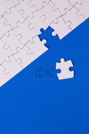 Téléchargez les photos : Missing jigsaw puzzle pieces. Business concept. Fragment of a folded white jigsaw puzzle and a pile of uncombed puzzle elements against - en image libre de droit