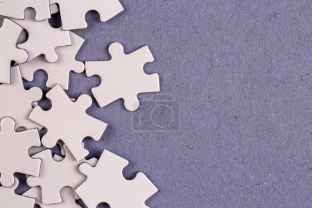 Foto de Missing jigsaw puzzle pieces. Business concept. Fragment of a folded white jigsaw puzzle and a pile of uncombed puzzle elements against - Imagen libre de derechos