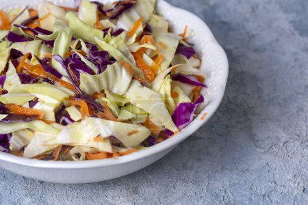 Téléchargez les photos : Salade de légumes frais au chou violet, chou blanc, laitue, carotte sur assiette blanche - en image libre de droit