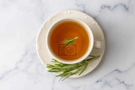 Foto de Taza de té de romero saludable con manojo de romero fresco sobre fondo rústico, concepto de bebida caliente de hierbas de invierno, salvia rosmarinus - Imagen libre de derechos