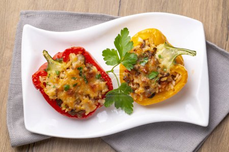 Photo for Stuffed peppers, halves of peppers stuffed with rice, dried tomatoes, herbs and cheese in a baking dish on a blue wooden table, top view. (Turkish name; biber dolmasi) - Royalty Free Image